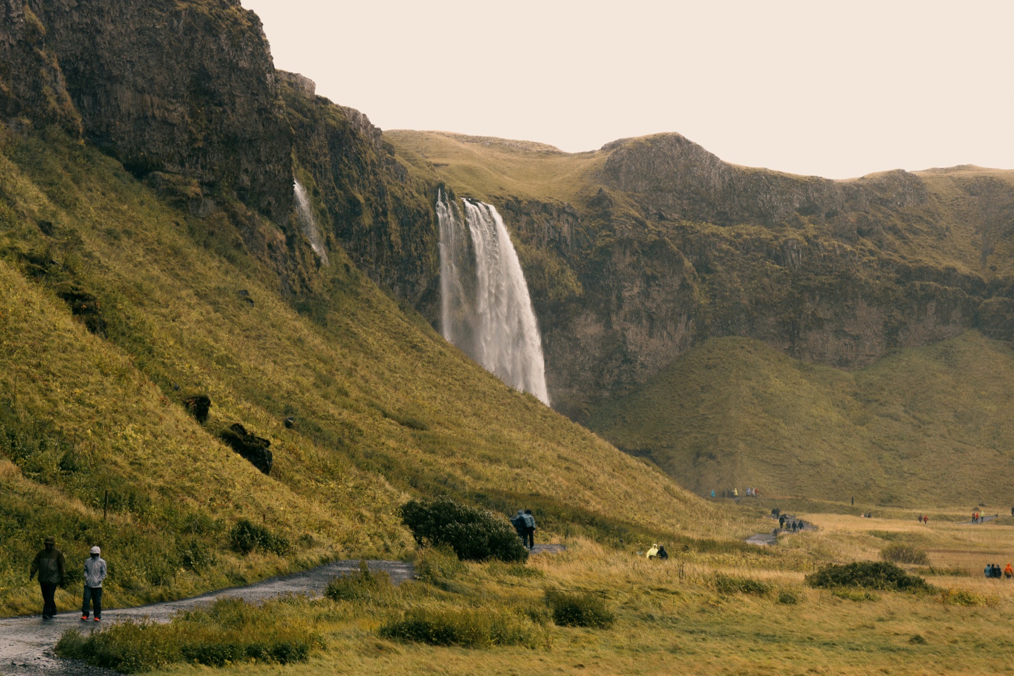 A waterfall cascading down a green mountainside at dusk